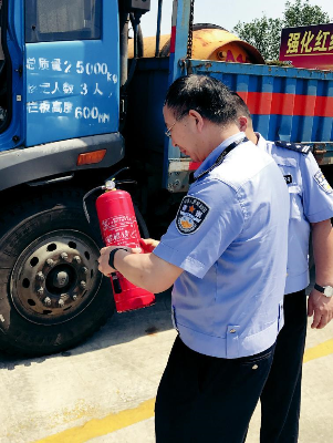  图：交警在检查危化品运输车辆的安全告示和灭火器配备情况。