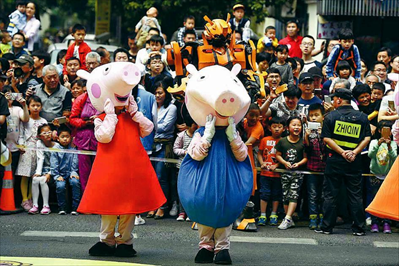 扮演成“小猪佩奇”的演员在巡游队伍中表演。新华社 记者 黄宗治摄