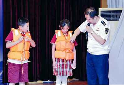 图：海事处工作人员指导学生正确穿戴救生衣。