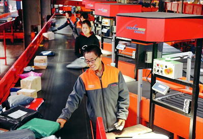 图：11月11日，工作人员在江苏省南通市一家快递公司分拣系统旁忙碌。新华社发